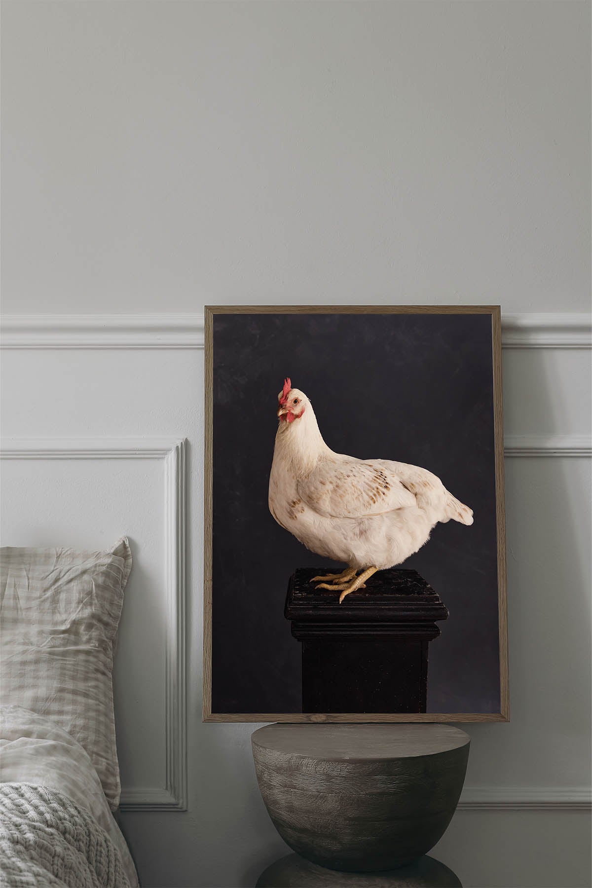 Fine Art Print Of A White Chicken Standing On A Black Plinth With A Black Background Framed On A Wall In An European Style Bedroom.