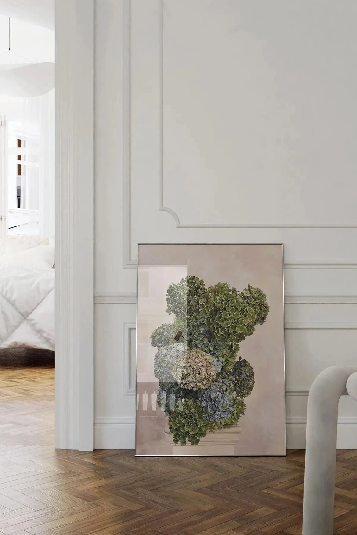 Fine art print of clustered hydrangea blooms in muted greens, blues and creams leaning against white panelled wall on herringbone timber floors in an elegant hallway