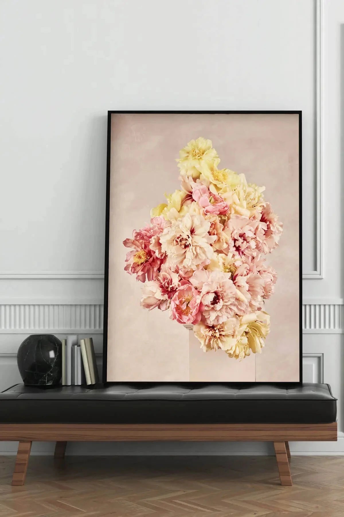 Fine art print of pink and yellow peonies arranged in a cluster on a soft blush background, displayed in black frame on dark console table