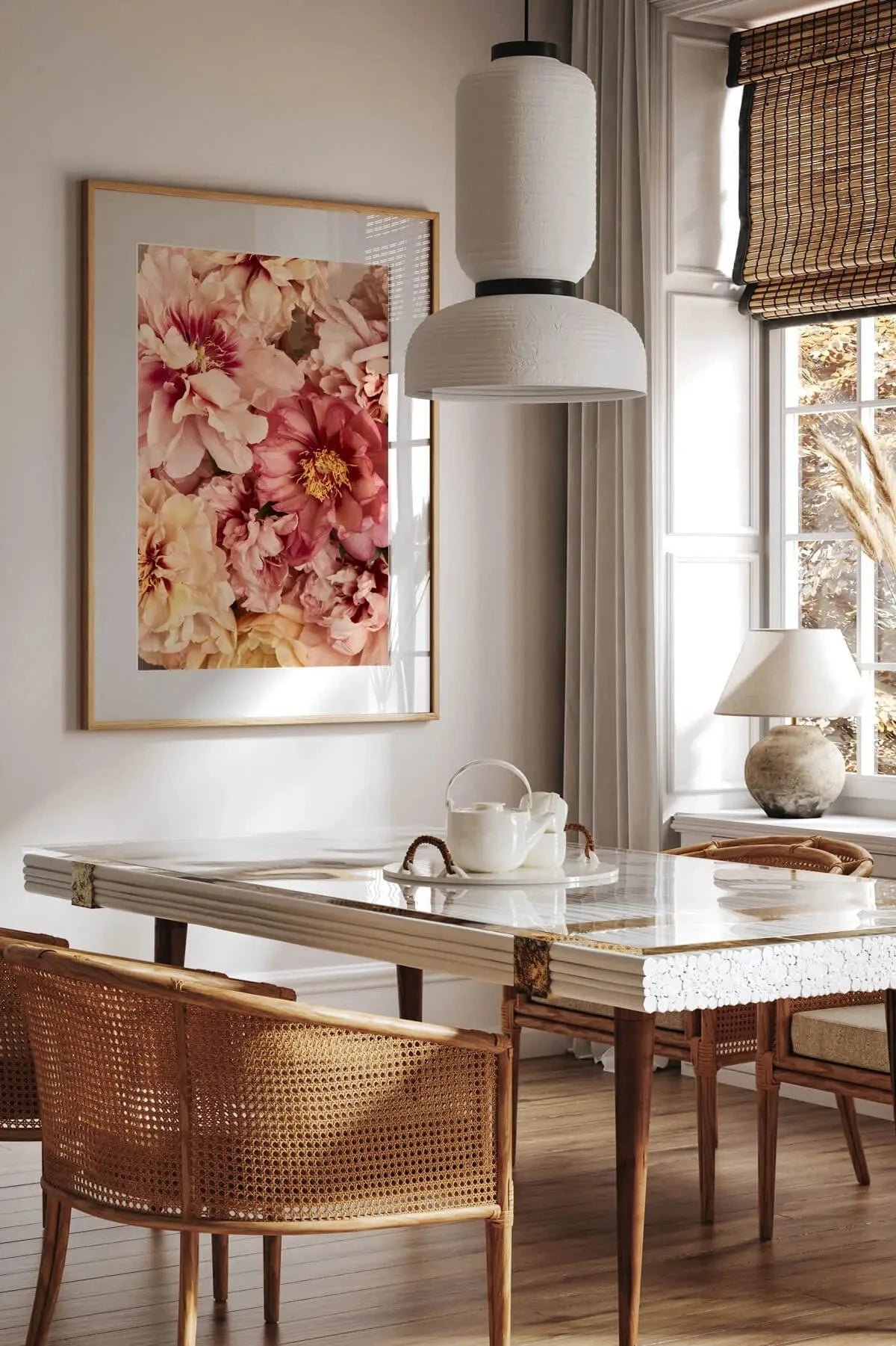 Fine art print of soft pink and cream peonies in full bloom hanging above a marble dining table in a light-filled room with natural timber accents