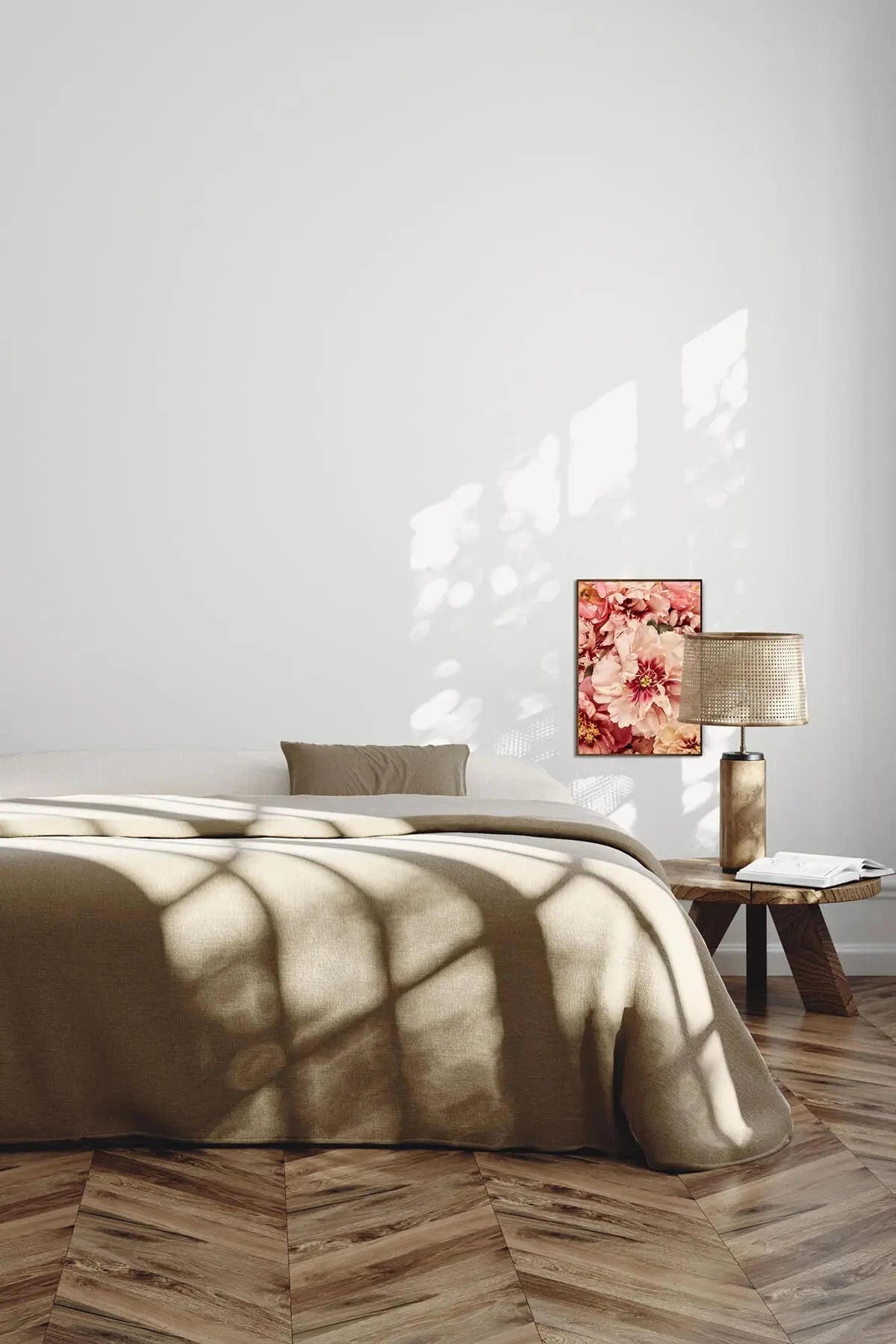 Fine art print of soft pink peonies in warm coral and blush tones above a bed with olive linen in a sunlit bedroom with herringbone floors.