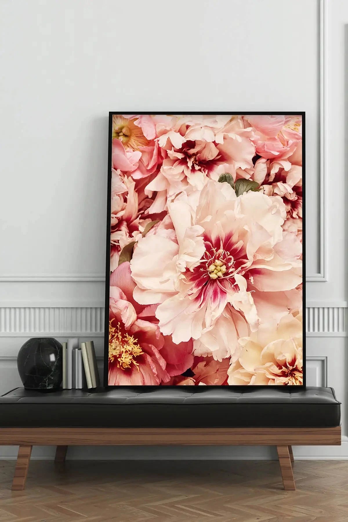 Fine art print of blush pink and cream peonies with deep burgundy centers displayed on a black bench against elegant wainscoting.