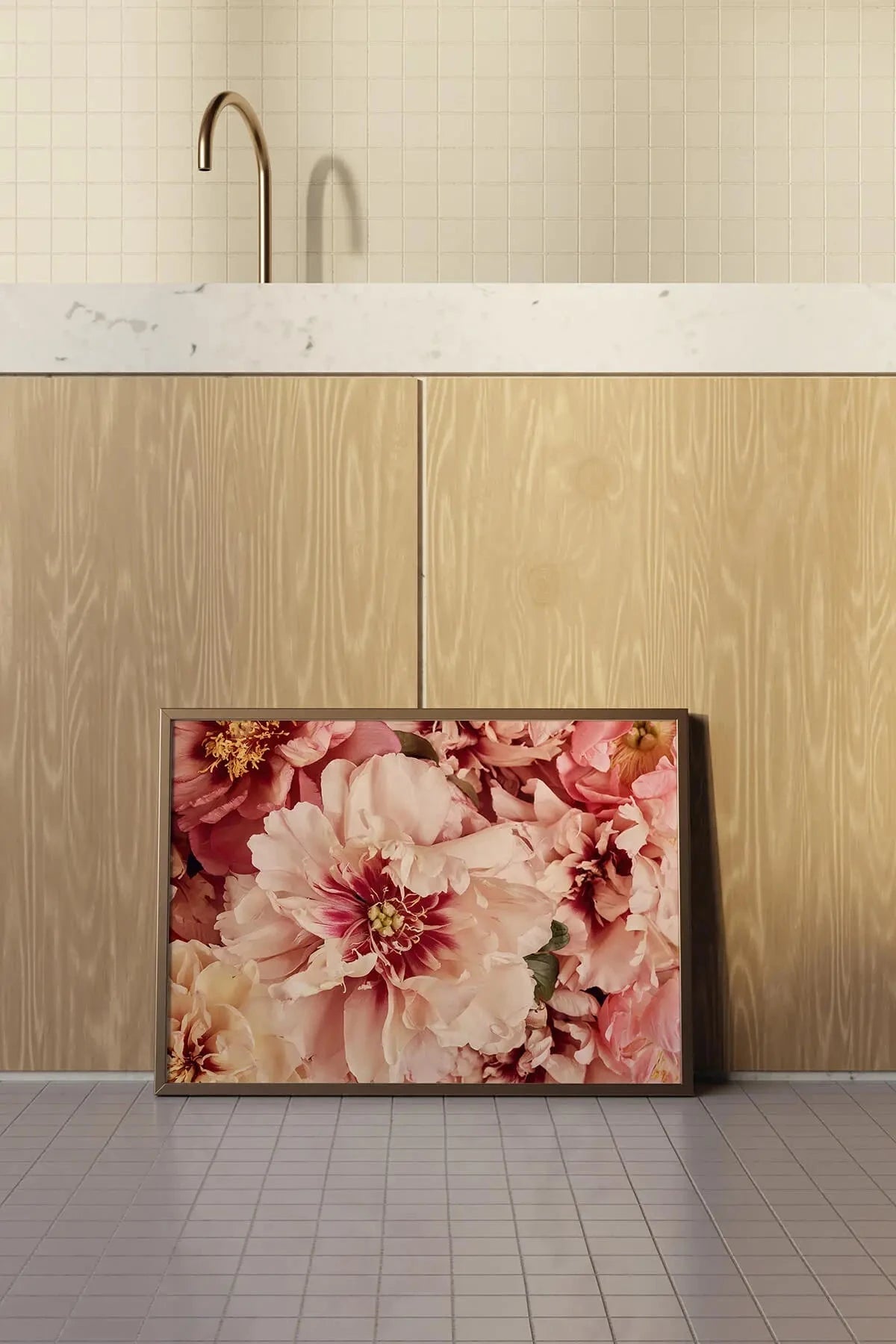 Fine art print of lush pink and blush peonies in full bloom leaning against light wood cabinetry beneath marble countertop in a modern kitchen